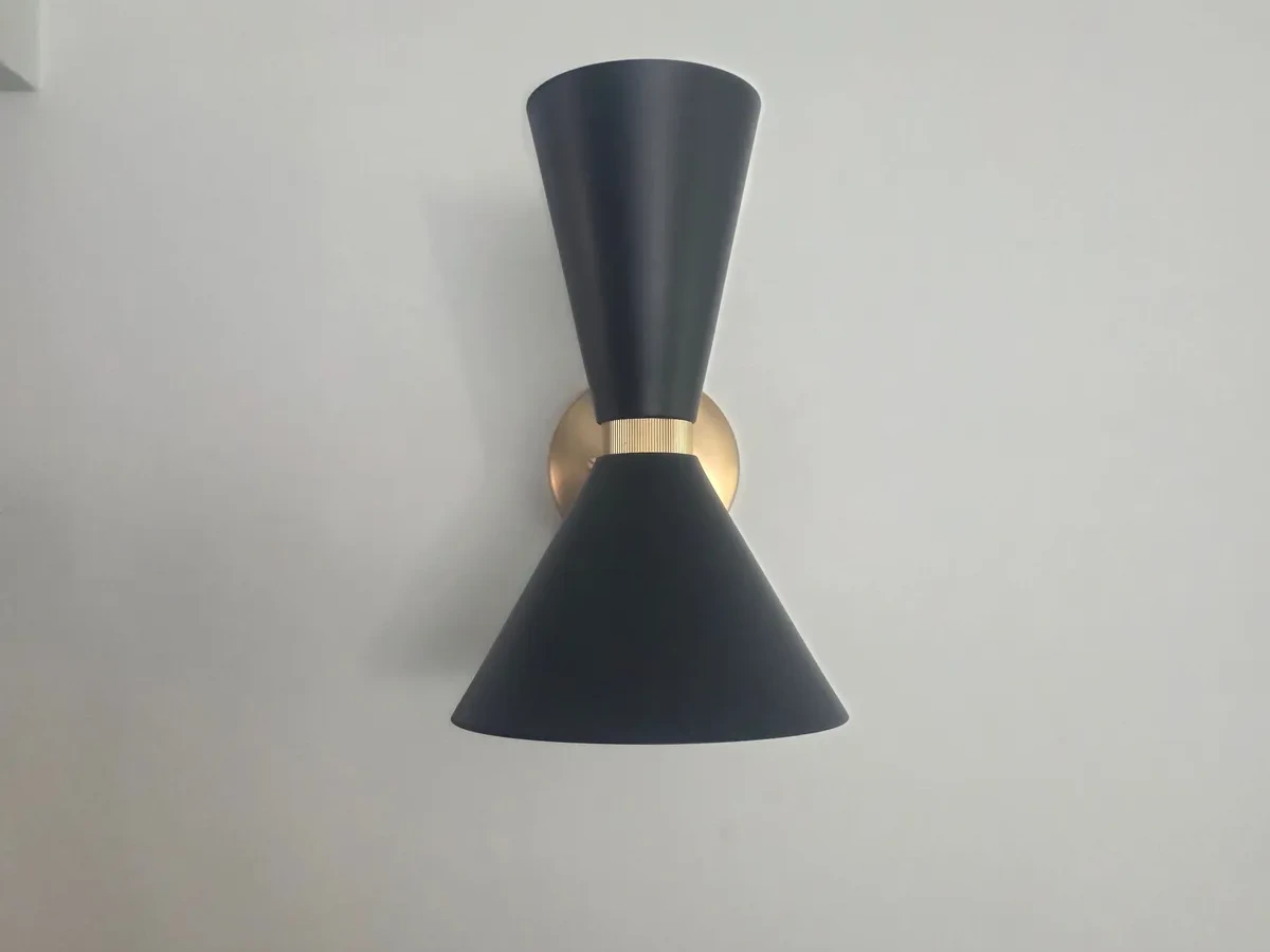 Black and brass double cone wall light fitted in a bathroom