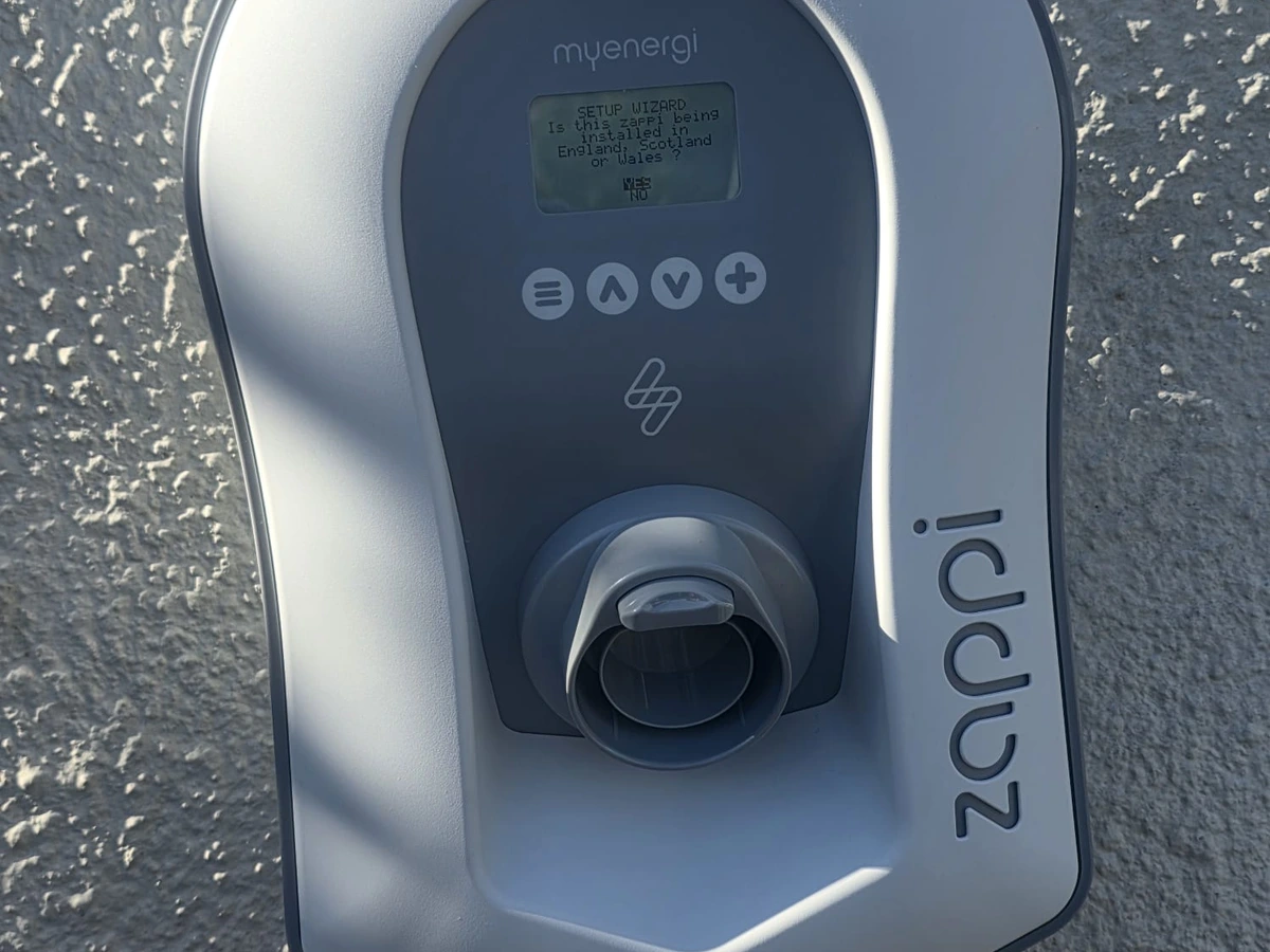 Close-up of a wall-mounted Myenergi Zappi EV charger showing its display, controls and cable holder